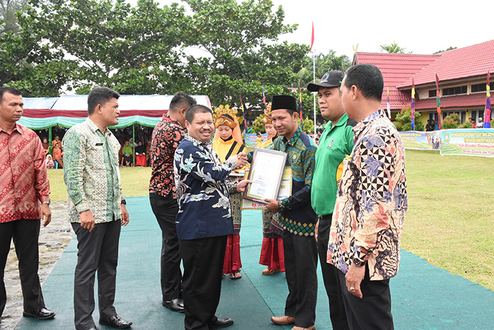 Bupati Bengkalis Amril Mukminin menyerahkan piagam penghargaan kepada Kepala Desa Teluk Lecah, Azmi, sebagai peraih terbaik I BBGRM Kabupaten Bengkalis 2018.